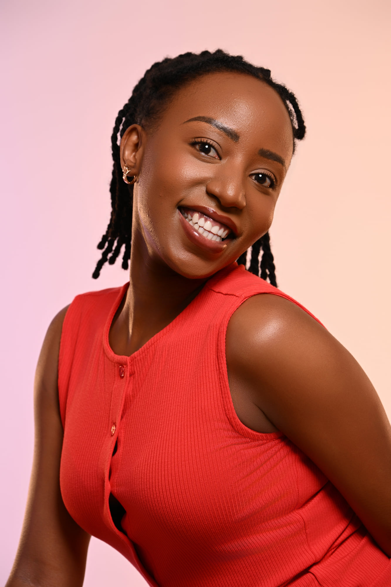 Beauty portrait of Lorna Ishimwe in a coral sleeveless top against a soft pink gradient.