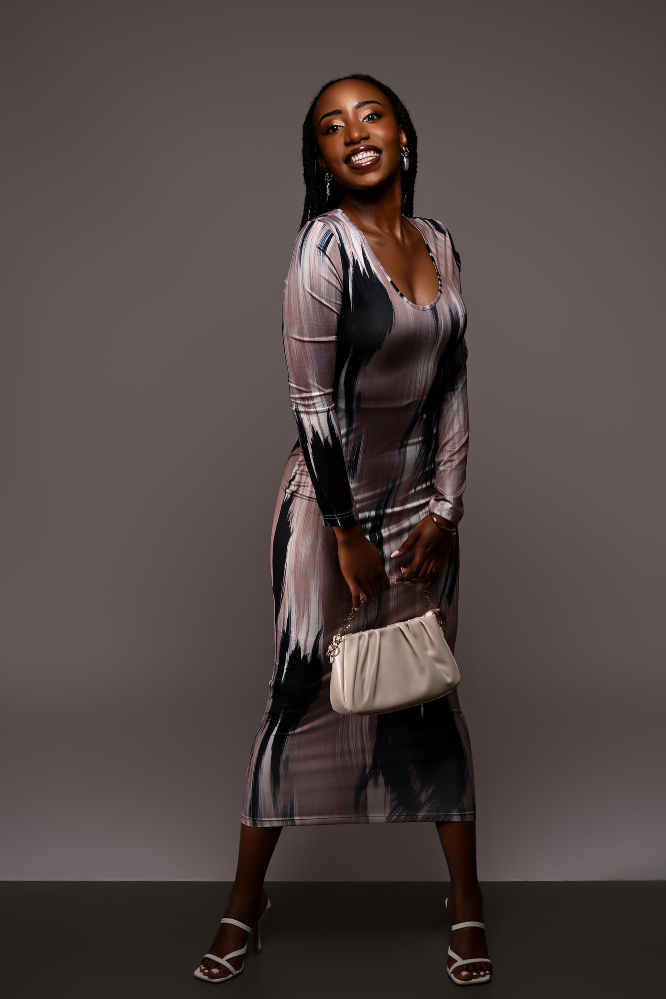 Lorna Ishimwe in a printed midi dress, turning towards the camera in studio light.