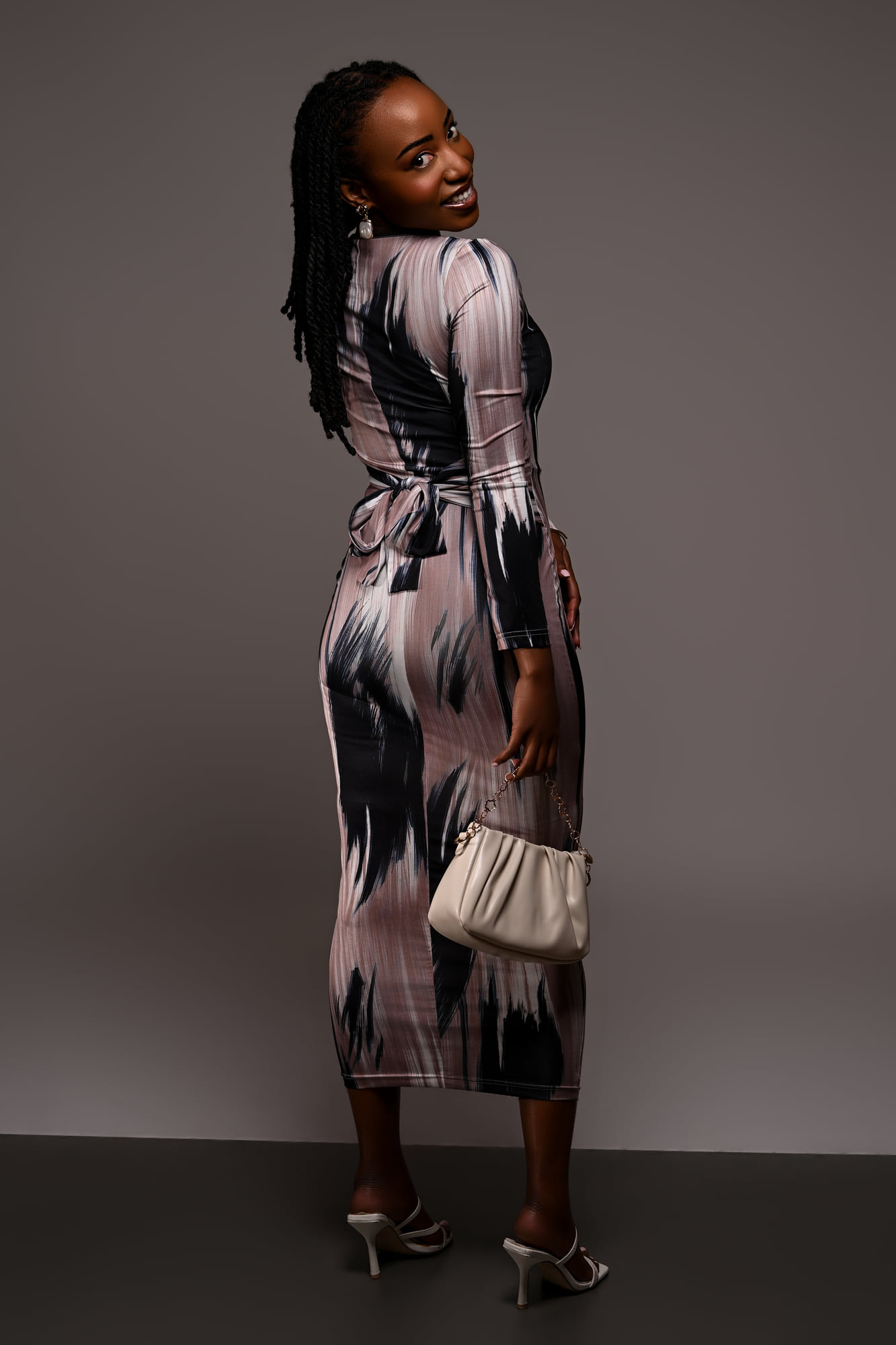 Lorna Ishimwe in a printed midi dress, three-quarter length studio pose.