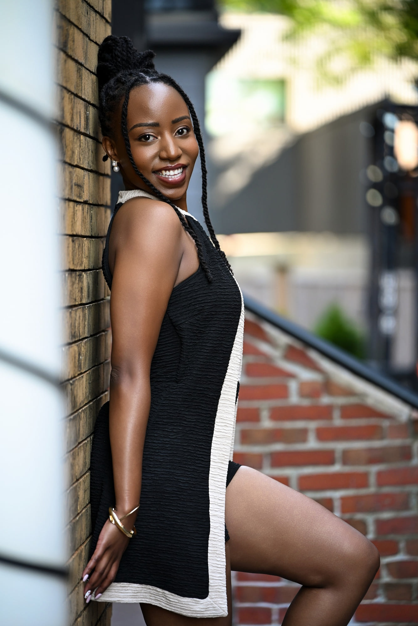 Lorna Ishimwe on location in a black and white outfit against an exposed brick wall.